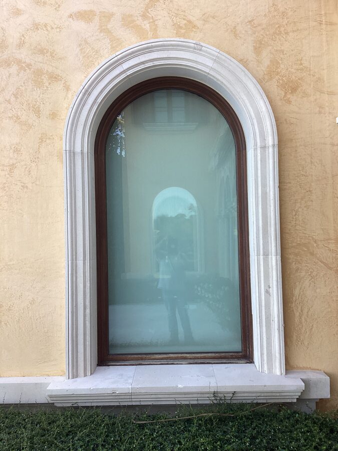 Arched window with limestone trim on Mediterranean yellow stucco