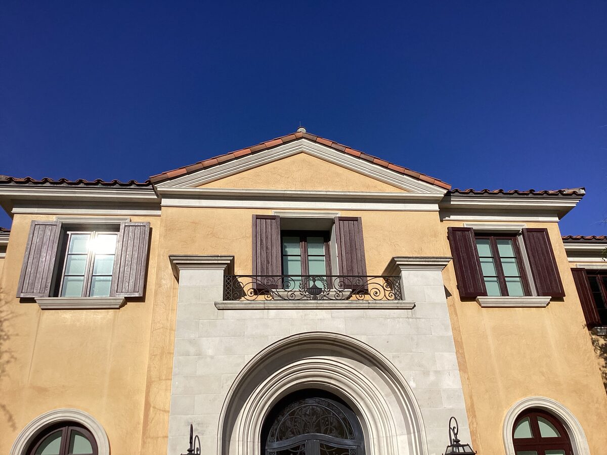 Yellow stucco facade with pediment and balcony