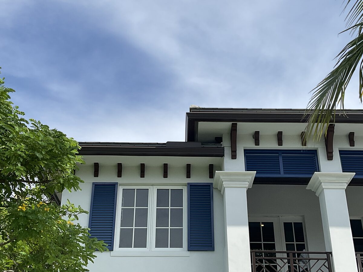 White exterior with blue shutters and dark corbels