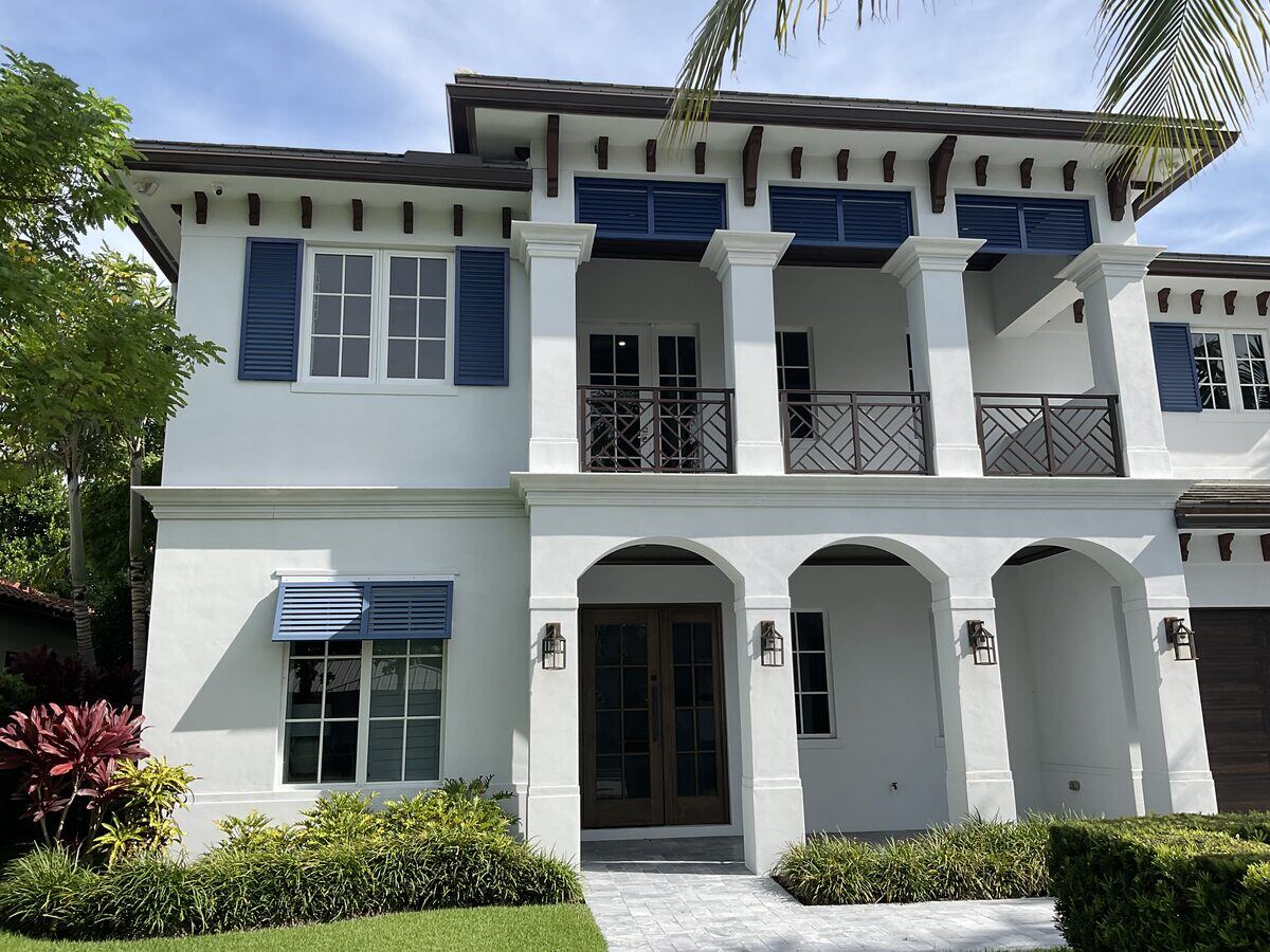 Two-story residence with navy shutters and arched entry