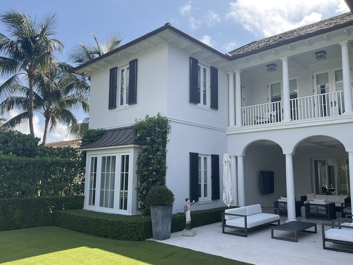 White stucco home with black shutters and balcony
