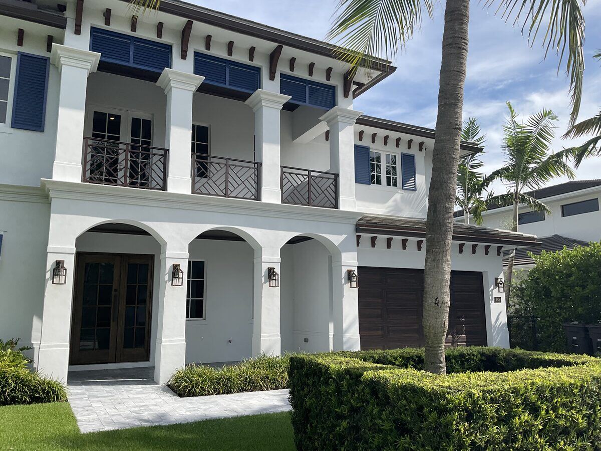 White stucco residence with blue shutters and arched garage