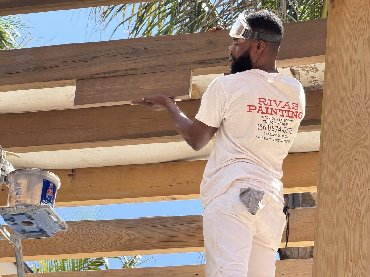 Rivas Painting crew member refinishing custom pergola, branded uniform