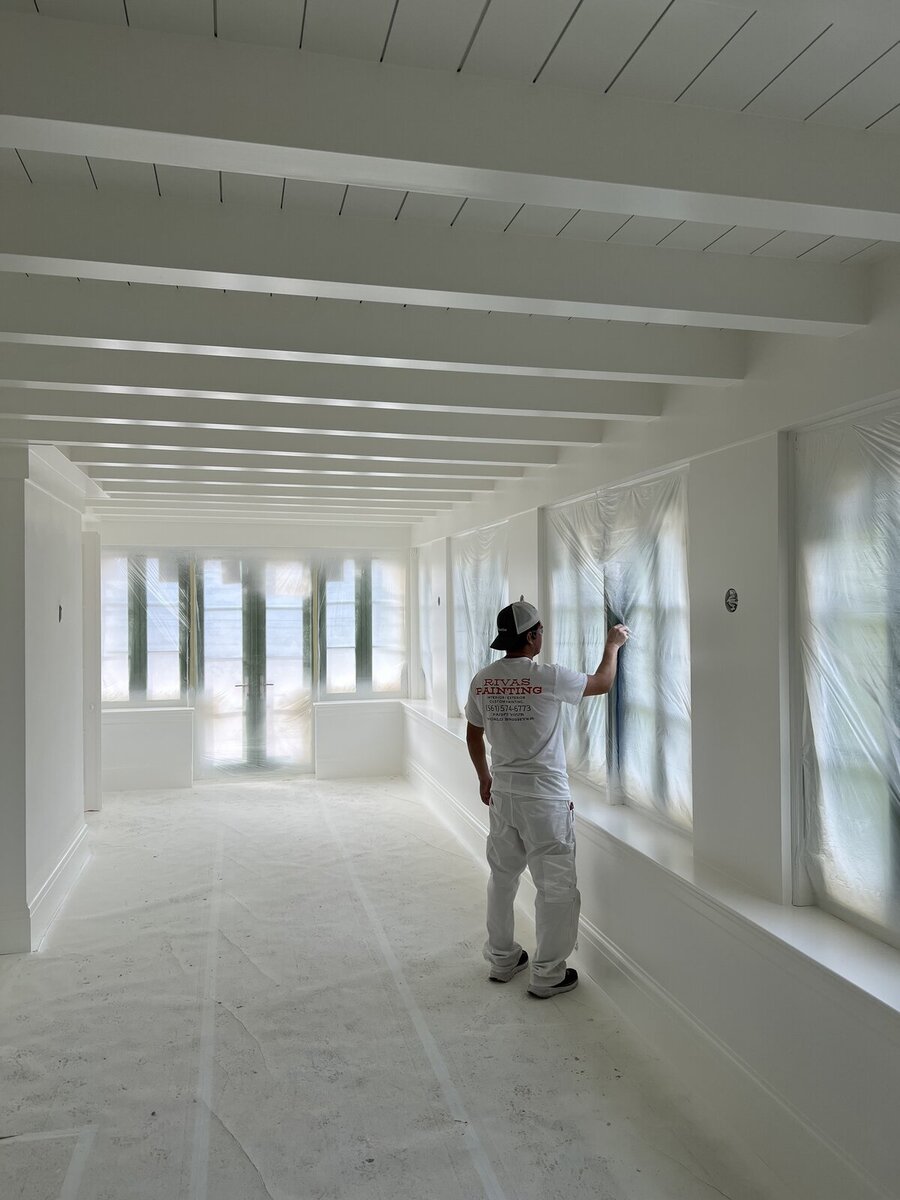 Rivas painter applying interior finish under exposed wood beams