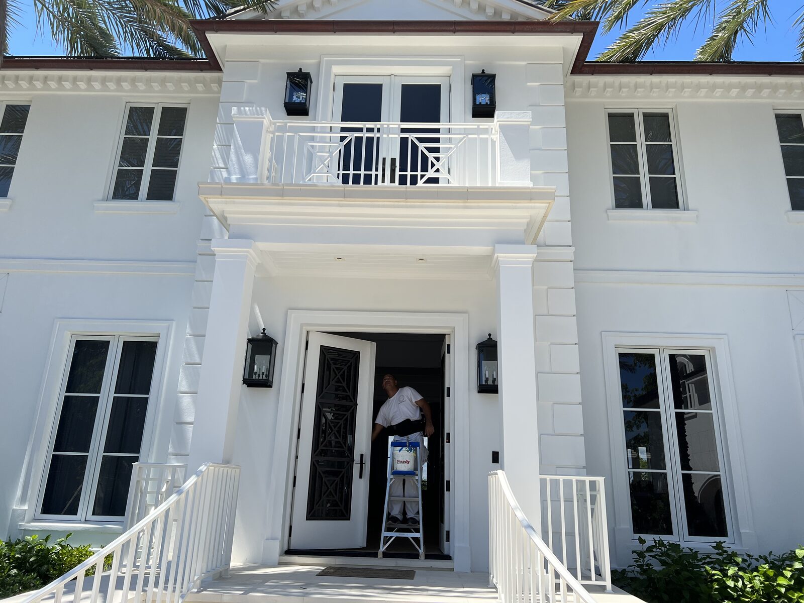 White stucco estate front entry with a painter refinishing the doorway