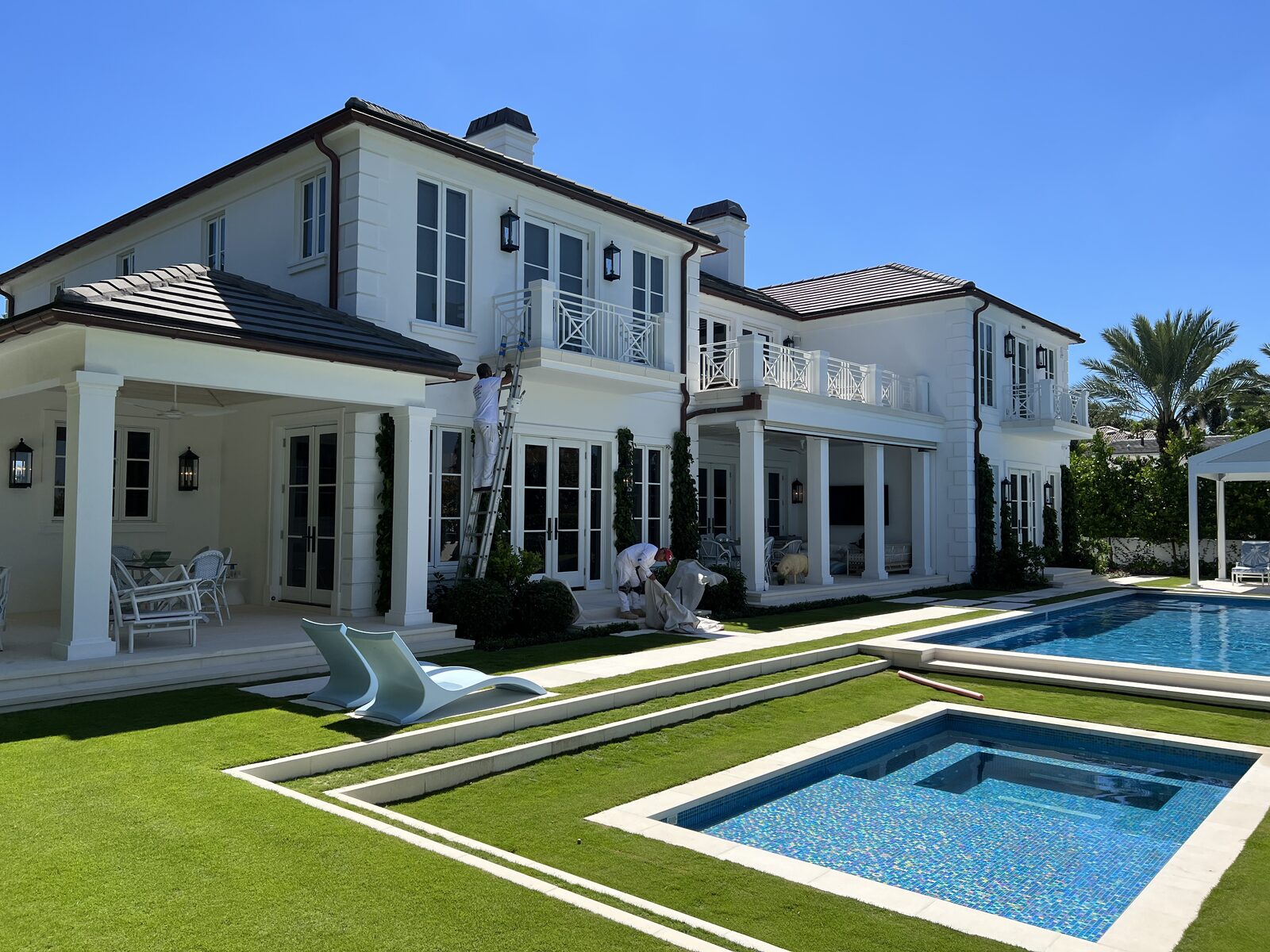Palm Beach estate exterior repaint in progress, crew working above the pool deck