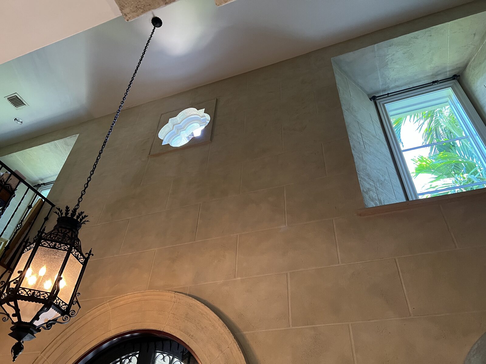 Faux limestone block plaster finish on a two-story entry wall