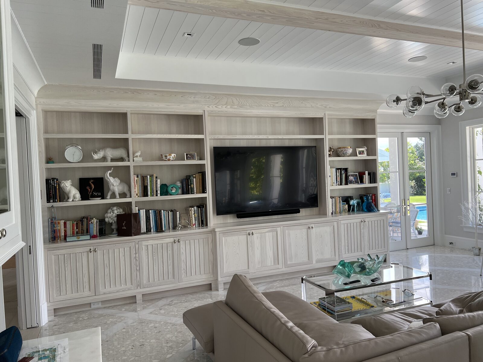 Limed oak built-in media wall and shiplap ceiling in a bright living room