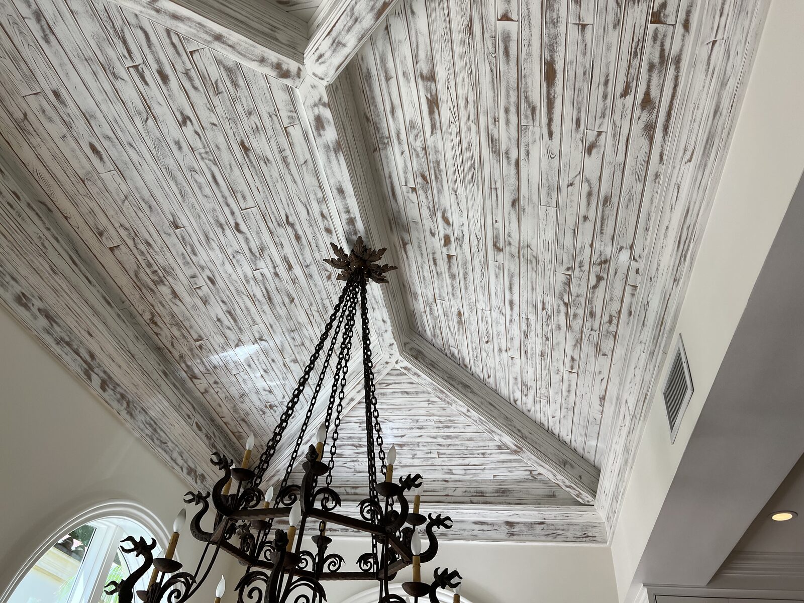 Wide view of the whitewashed plank vault ceiling and arched windows